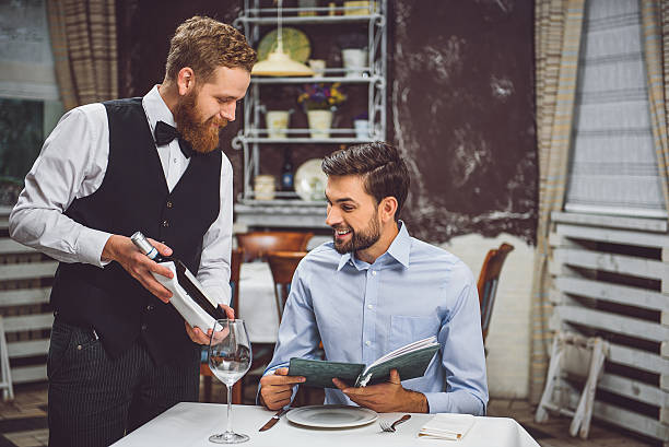 cameriere precauzionale che offre vino al visitatore - restaurant waiter table wait staff foto e immagini stock