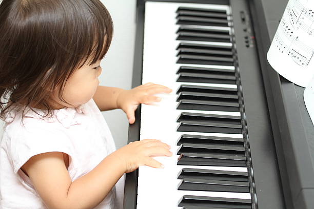 Japanese girl playing a piano (1 year old) Japanese girl playing a piano (1 year old) girl playing piano stock pictures, royalty-free photos & images
