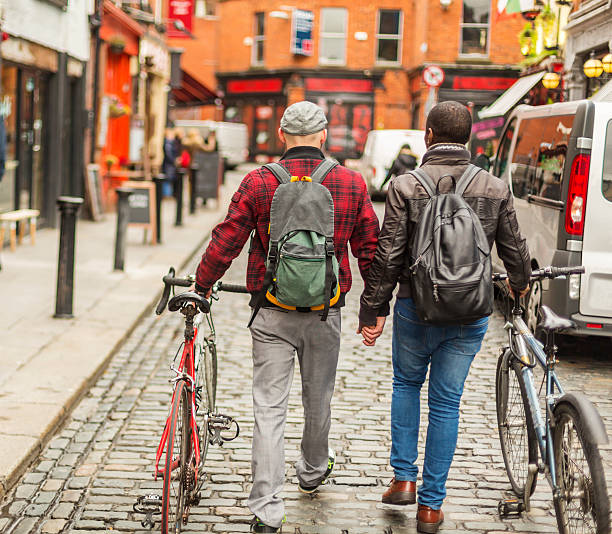 pareja gay de raza mixta con bicicletas en la ciudad - dublin ireland urban road people real people fotografías e imágenes de stock