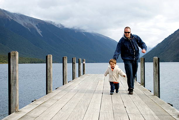 Father and Son on Pier, Nelson Lakes, New Zealand A Man and Boy run down Pier at Nelson Lakes, in the Tasman Region of New Zealand's South Island. nelson city new zealand stock pictures, royalty-free photos & images