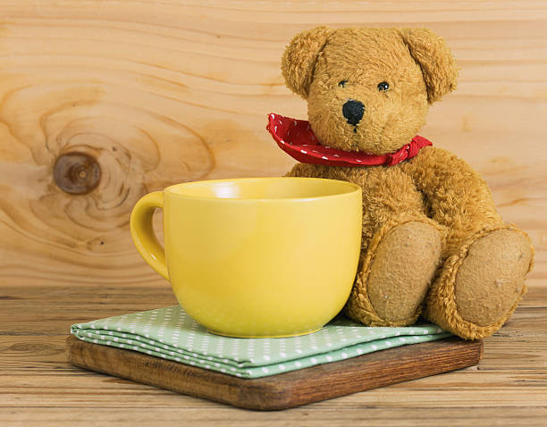 istock Yellow empty cup coffee on fabric with teddy bear sitting. 627280674