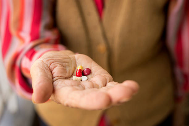 senior woman holding pills stock photo