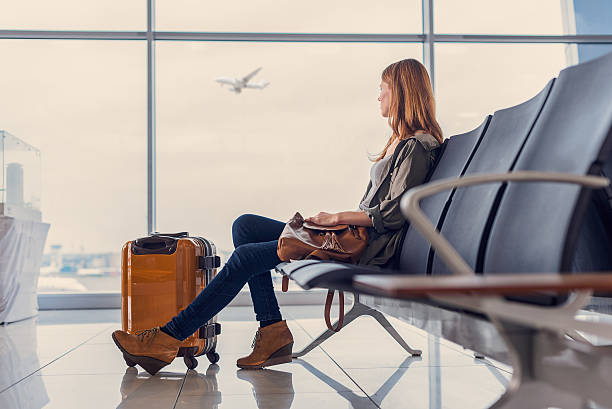 Smiling girl waiting for boarding Start of her journey. Beautiful young woman looking out window at flying airplane while waiting boarding on aircraft in airport lounge airport stock pictures, royalty-free photos & images