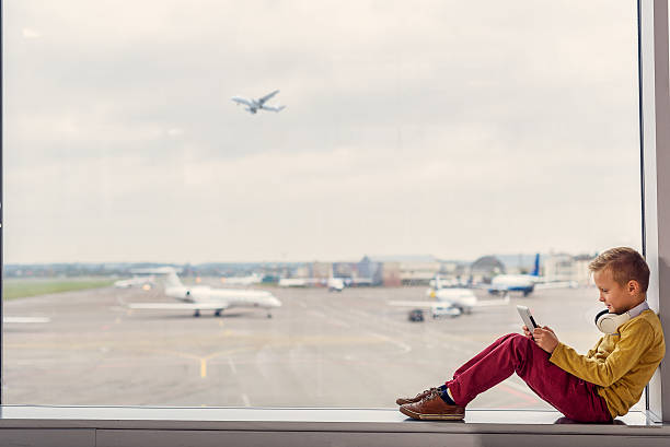 ragazzino seduto all'aeroporto - full length windows foto e immagini stock
