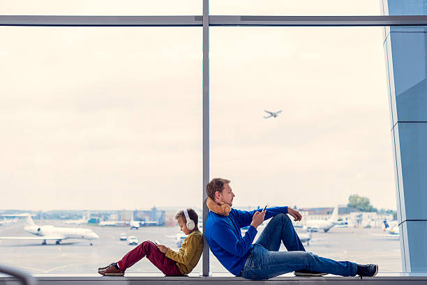 pai e filho esperando para embarcar no aeroporto - digital tablet family father offspring - fotografias e filmes do acervo