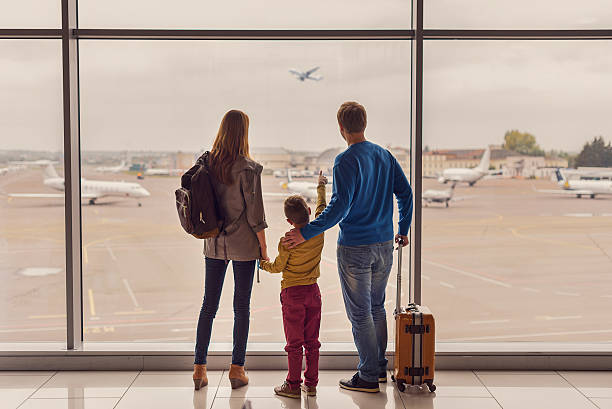 familie schaut aus dem fenster am flughafen - full length windows stock-fotos und bilder