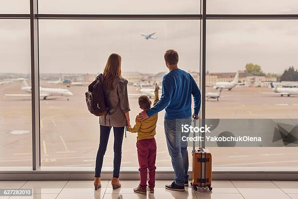 Familia Mirando Por La Ventana Del Aeropuerto Foto de stock y más banco de imágenes de Familia - Familia, Aeropuerto, Viajes