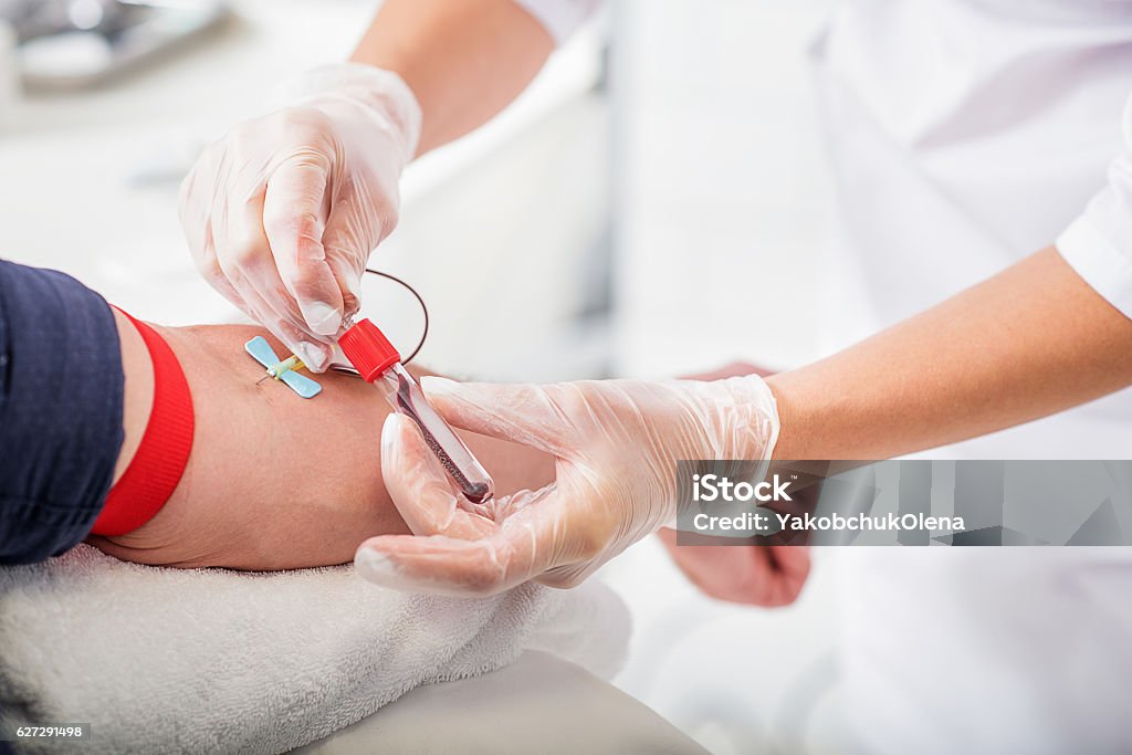 General practitioner doing blood test Close up of doctor hands taking blood from male vein into tube by catheter Blood Donation Stock Photo