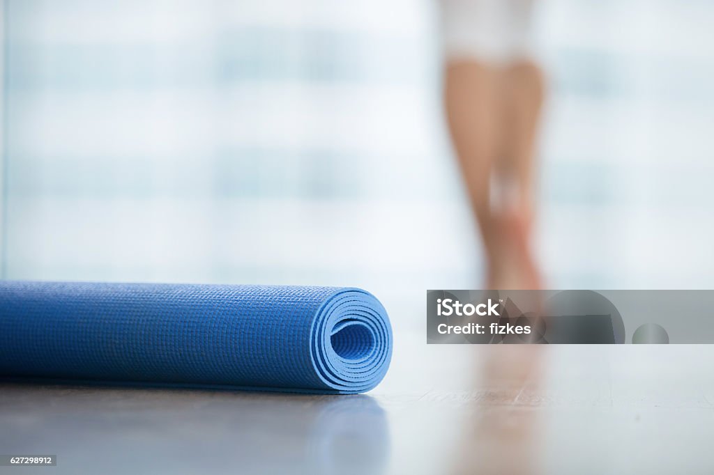 Close up of yoga, fitness mat Close up of yoga, fitness, foam exercise mat fix in a roll in living room or fitness center, blurred female body at the background, resting after yoga, fitness class. Healthy lifestyle concept Mattress Stock Photo