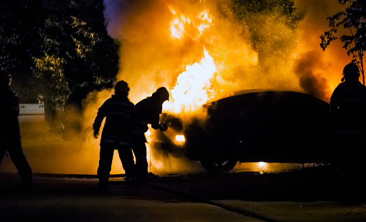 Firemen fighting a flaming car during night time