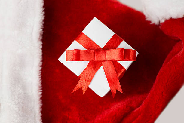 istock White gift box with red ribbon on Santa Claus hat 627314528