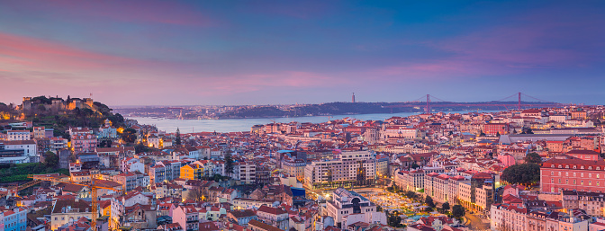 Image of Lisbon, Portugal during dramatic sunrise. This is composite of two horizontal images stitched together in photoshop.