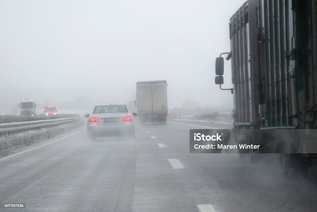 cars, trucks and rescue vehicle driving in dangerous winter weather cars, trucks and a rescue vehicle driving in dangerous winter weather with poor visibility during snow and rain on the highway, concept for safety in traffic, copy space Rain Stock Photo