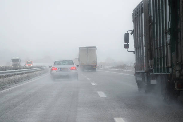 cars, trucks and rescue vehicle driving in dangerous winter weather cars, trucks and a rescue vehicle driving in dangerous winter weather with poor visibility during snow and rain on the highway, concept for safety in traffic, copy space truck rain stock pictures, royalty-free photos & images