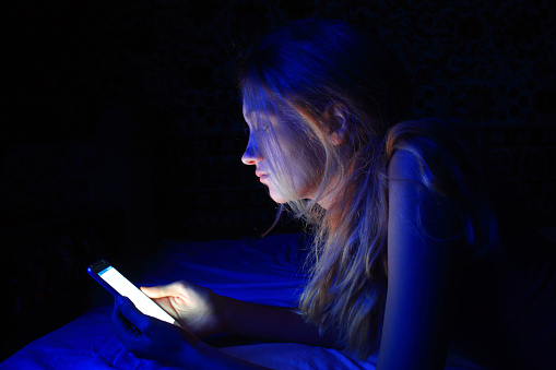 young woman using the smart phone on bed before sleep