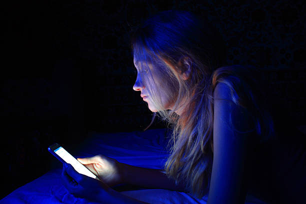 young woman using the smart phone on bed before sleep - kvinna telefonbedragare bildbanksfoton och bilder