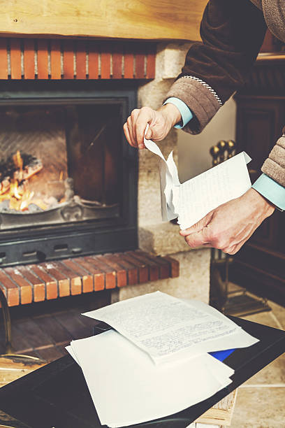 istock Hands tear sheets in bathrobe in front of burning fireplace 627354794