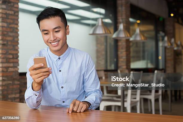 Smiling Asian Man Using Smartphone At Cafe Table Stock Photo - Download Image Now - Asian and Indian Ethnicities, Men, Telephone