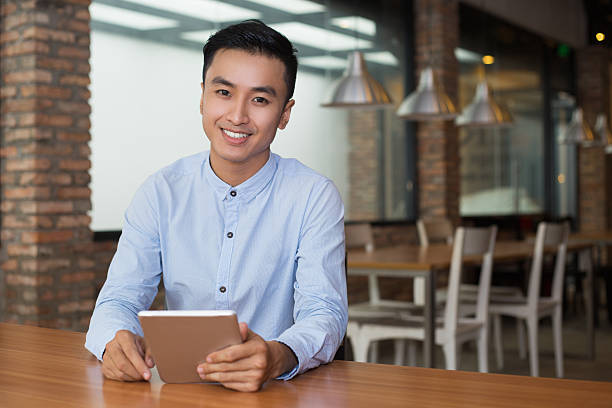 istock Smiling Man Sitting at Cafe Table with Tablet 627356306