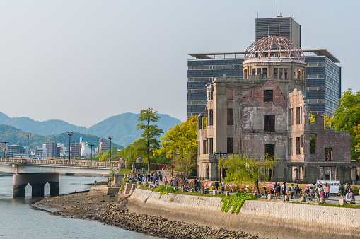 Hiroshima, Japan - April 28, 2013: Tourists walk between the river and  the UNESCO listed Atomic Bomb Memorial Dome in Hiroshima, Japan.