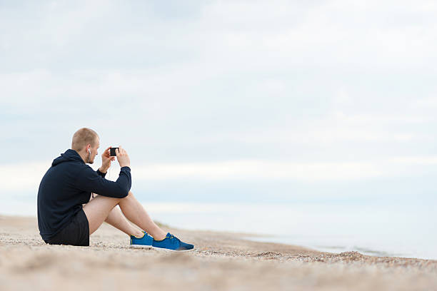 homme sur la plage écoutant de la musique - privacy partition photos et images de collection