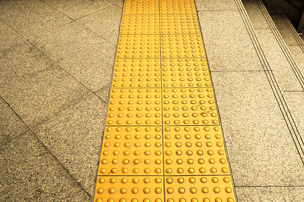 istock Sidewalk guides for blind. Yellow concrete cobblestones on walkway 627371678
