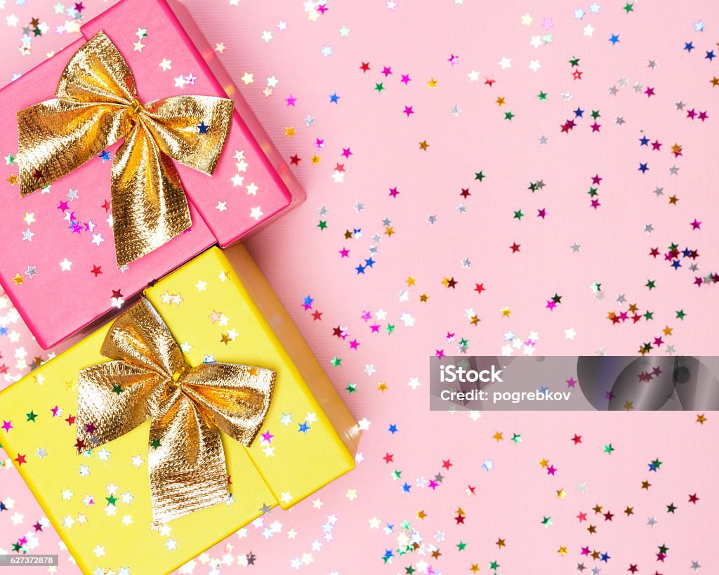 Celebratory background with color gift boxes and confetti Celebratory background with two color gift boxes, golden bows and sparkling confetti Gift Box Stock Photo