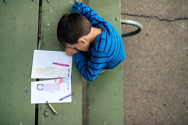 Young boy looking sad at drawing of a broken family Young boy looking sad at drawing of a broken family child abuse photos stock pictures, royalty-free photos & images