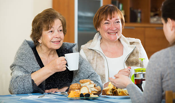 istock Senior women talking with girl while tea drinking 627373168