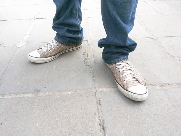 istock Men's feet in sneakers standing on a concrete background 627373562