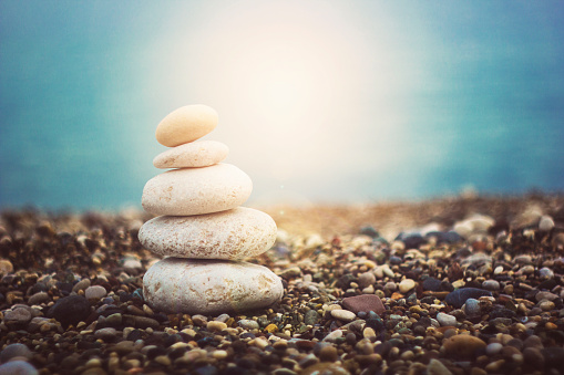 Zen like balanced stones on a pebble beach during sunset, lens flare. Alternative therapy.