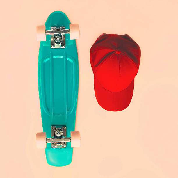 Fashion set. Skateboard, baseball cap on beige background, top view stock photo