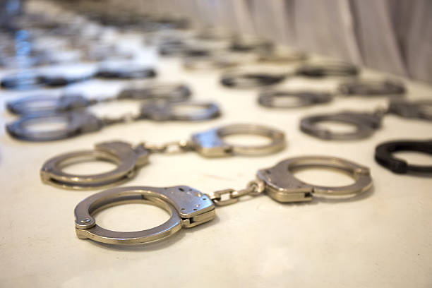 row of law enforcement silver metal  handcuffs on white table row of law enforcement silver metal  handcuffs prepare for training on white table wrongdoer stock pictures, royalty-free photos & images