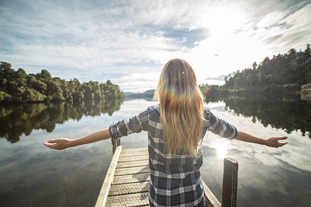 jovem relaxa em cais sobre lago, braços estendidos - lake tranquil scene landscape zen like - fotografias e filmes do acervo