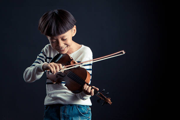 istock boy playing a Violin isolated over a black background 627447334