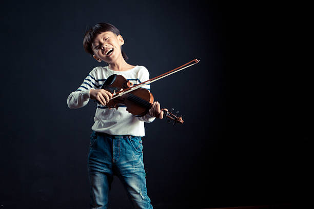 istock boy playing a Violin isolated over a black background 627447378