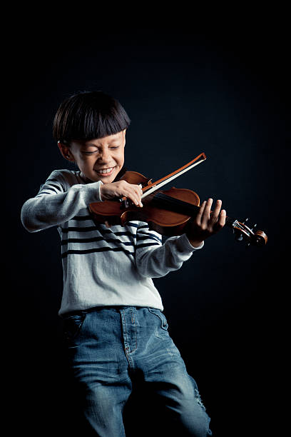 istock boy playing a Violin isolated over a black background 627447420