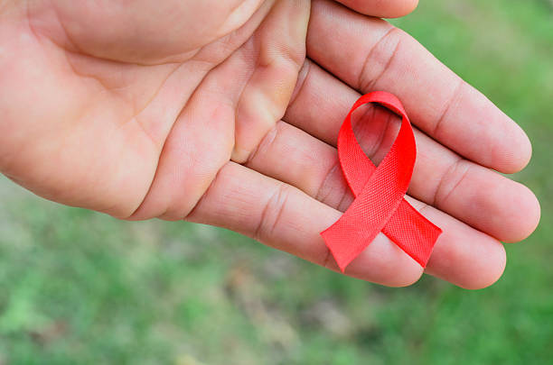 istock Red ribbon on palm on green background 627448568