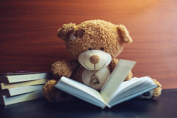 istock toy bear reading an interesting book. concept of baby learning 627453532