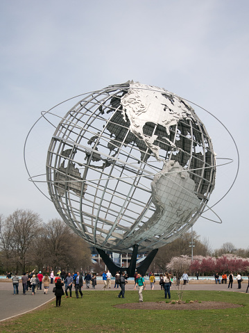 New York City, NY, USA - 22 April 2014: People walking around the Unisphere on the site of the 1964 World's Fair in New York City.  Flushing Meadows Park in Queens on a spring day.
