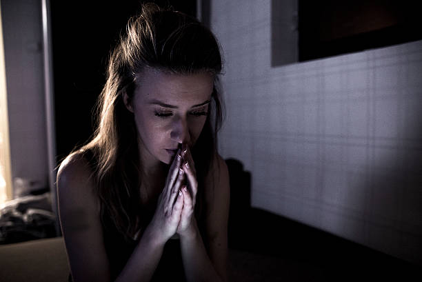 istock Sad Beautiful  young woman in darkness praying 627456808