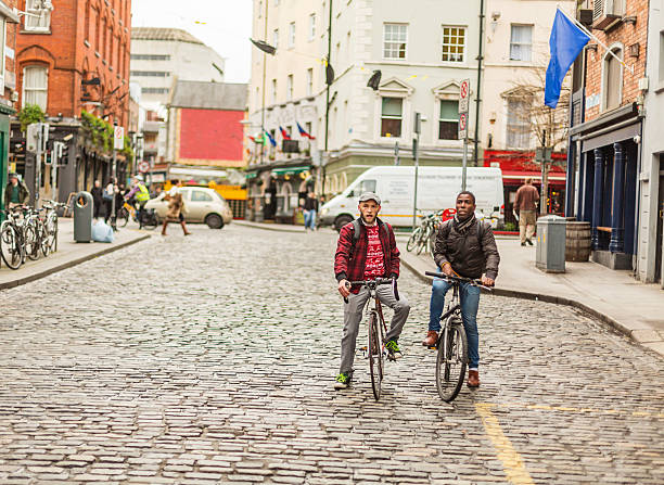 pareja gay de raza mixta con bicicletas en la ciudad - dublin ireland urban road people real people fotografías e imágenes de stock