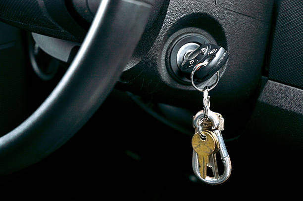 Car keys in the ignition Shot of Car key and house key dangling from the ignition of car ignition photos stock pictures, royalty-free photos & images
