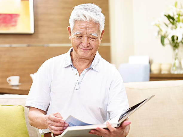 istock senior asian man relaxing reading a book at home 627473040