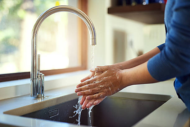 Washing up before dinner Shot of an unrecognizable woman washing her hands in the kitchen sink Tap stock pictures, royalty-free photos & images