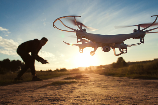 Pilot running drone at sunset light, free space