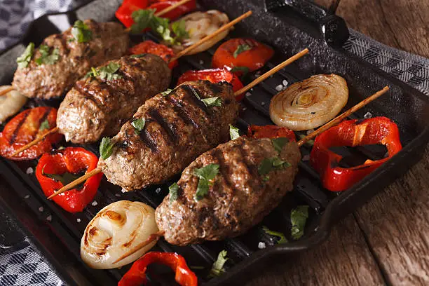 Kyufta kebabs with grilled vegetables close-up on a grill pan. horizontal
