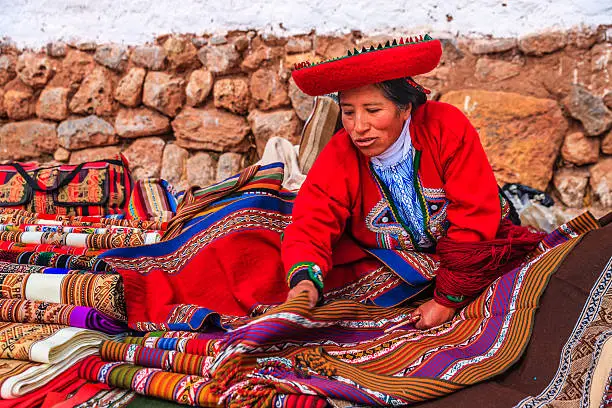 Peruvian woman selling souvenirs at Inca ruins. The Sacred Valley of the Incas or Urubamba Valley is a valley in the Andes  of Peru, close to the Inca capital of Cusco and below the ancient sacred city of Machu Picchu. The valley is generally understood to include everything between Pisac  and Ollantaytambo, parallel to the Urubamba River, or Vilcanota River or Wilcamayu, as this Sacred river is called when passing through the valley. It is fed by numerous rivers which descend through adjoining valleys and gorges, and contains numerous archaeological remains and villages. The valley was appreciated by the Incas due to its special geographical and climatic qualities. It was one of the empire's main points for the extraction of natural wealth, and the best place for maize production in Peru.http://bhphoto.pl/IS/peru_380.jpg