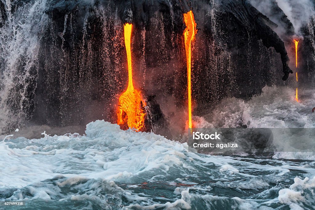 Molten lava flowing into the Pacific Ocean on Big Island Molten lava flowing into the Pacific Ocean on Big Island, forming a lava fall along with waterfall Erupting Stock Photo
