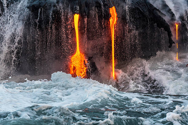 Molten lava flowing into the Pacific Ocean on Big Island Molten lava flowing into the Pacific Ocean on Big Island, forming a lava fall along with waterfall pele stock pictures, royalty-free photos & images